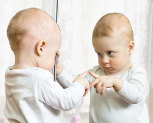 Ребеночек кривляется в зеркале