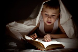 Ребенок читает книгу при плохом освещении